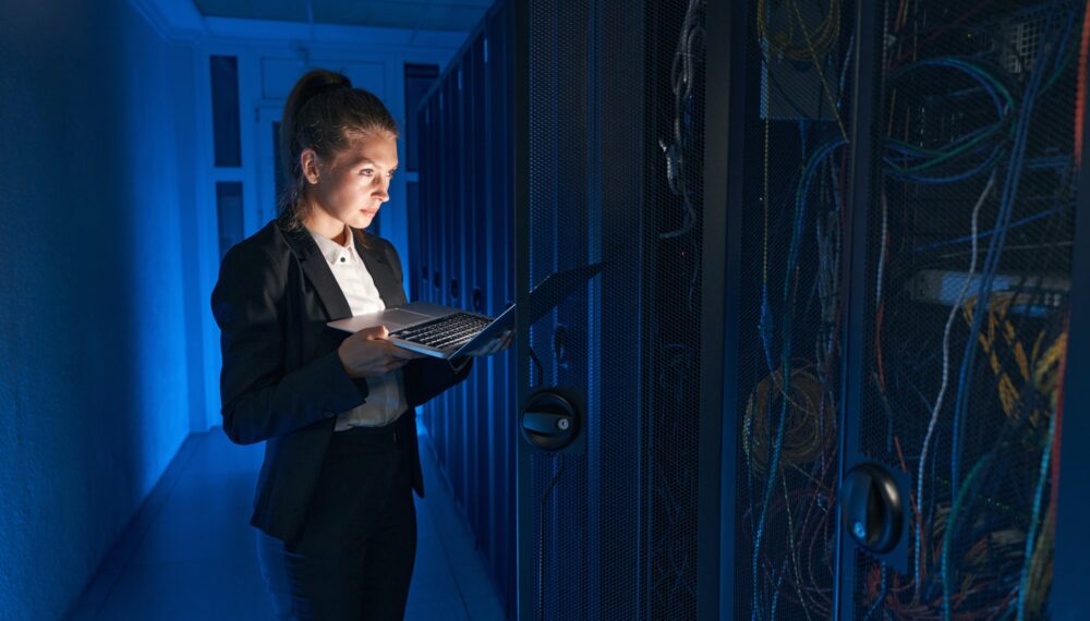 Confident system administrator working on laptop in data center