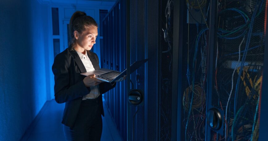 Confident system administrator working on laptop in data center