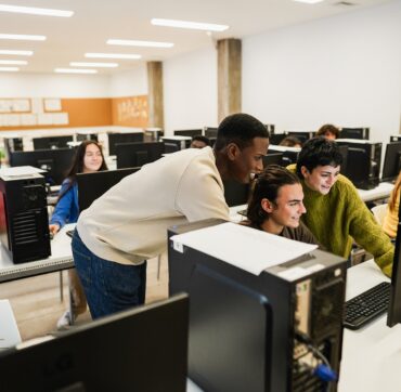 Young multiracial students using computers during business class at school