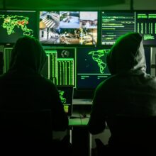 Hackers working on computers showing world maps and security camera footage Hackers working on computers showing world maps and security camera footage