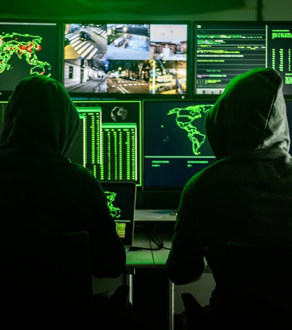 Hackers working on computers showing world maps and security camera footage
