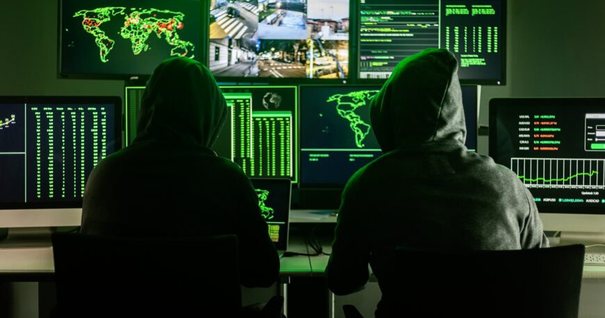 Hackers working on computers showing world maps and security camera footage