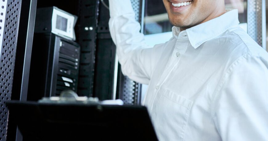 Server room, IT support and database with a man programmer working on a mainframe in a data center.